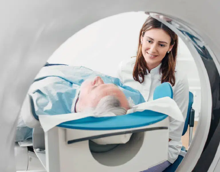 patient entering a ct scanner with a technologist at their side