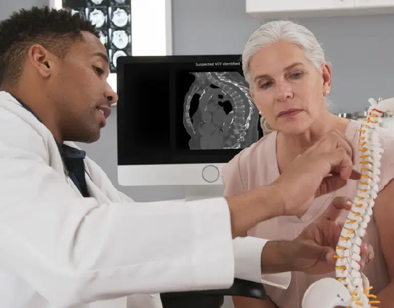 physician explaining a vertebral compression fracture to a patient with a spine model